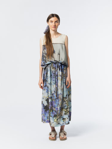 Front view of model wearing the Anntian Silkdress in Print Q, a sleeveless relaxed-fit silk dress in a multicolour floral print with blue tones, featuring an elastic waist with drawstring