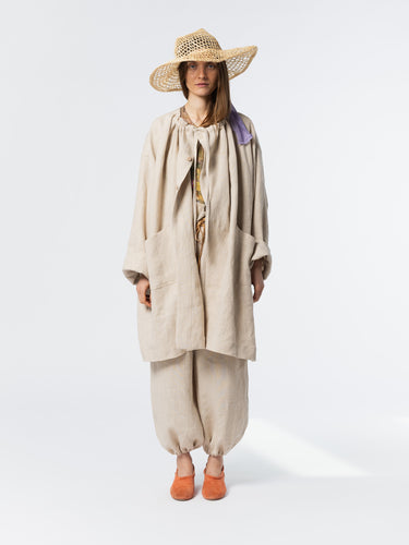 Front view of model wearing the Anntian Trench Jacket Hemp in Natural, an off-white loose-fit hemp jacket with an adjustable drawstring neckline, one size