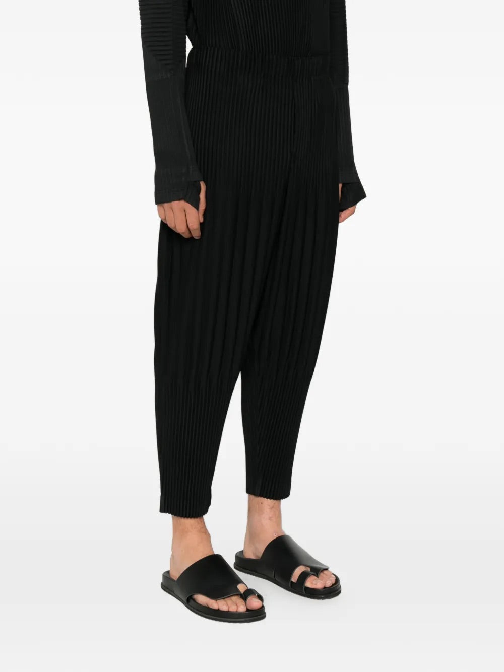 Model wearing Homme Plissé Issey Miyake black pleated pants side view