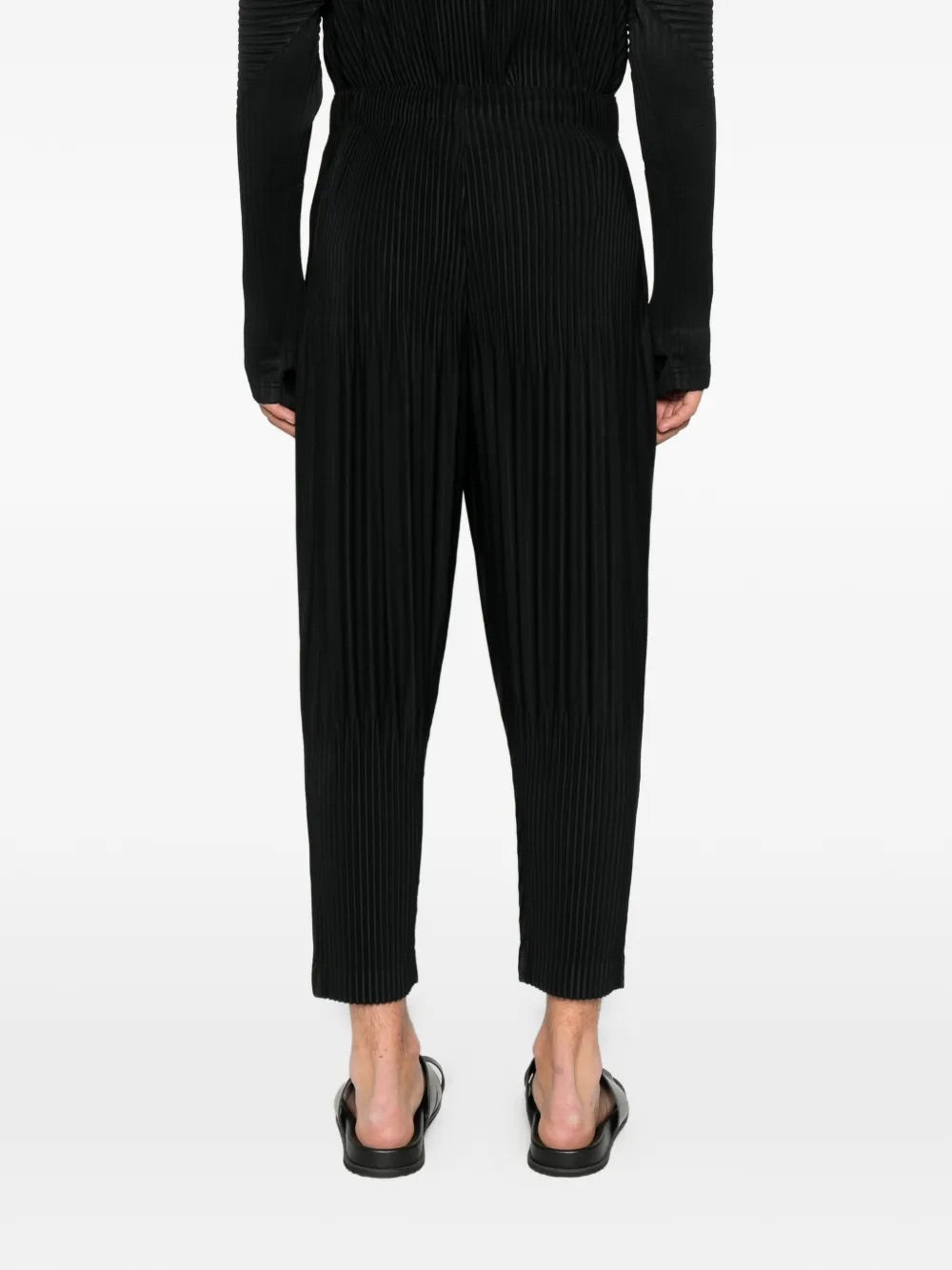 Model wearing Homme Plissé Issey Miyake black pleated pants back view