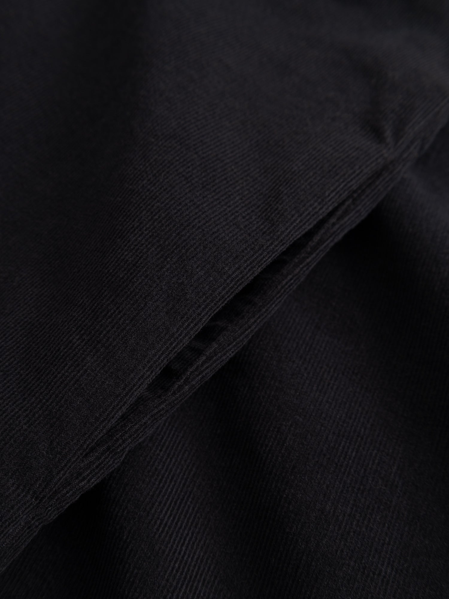 Detail close-up of the Painter Dress highlighting the corduroy ribs, boat neckline, and pocket opening.
