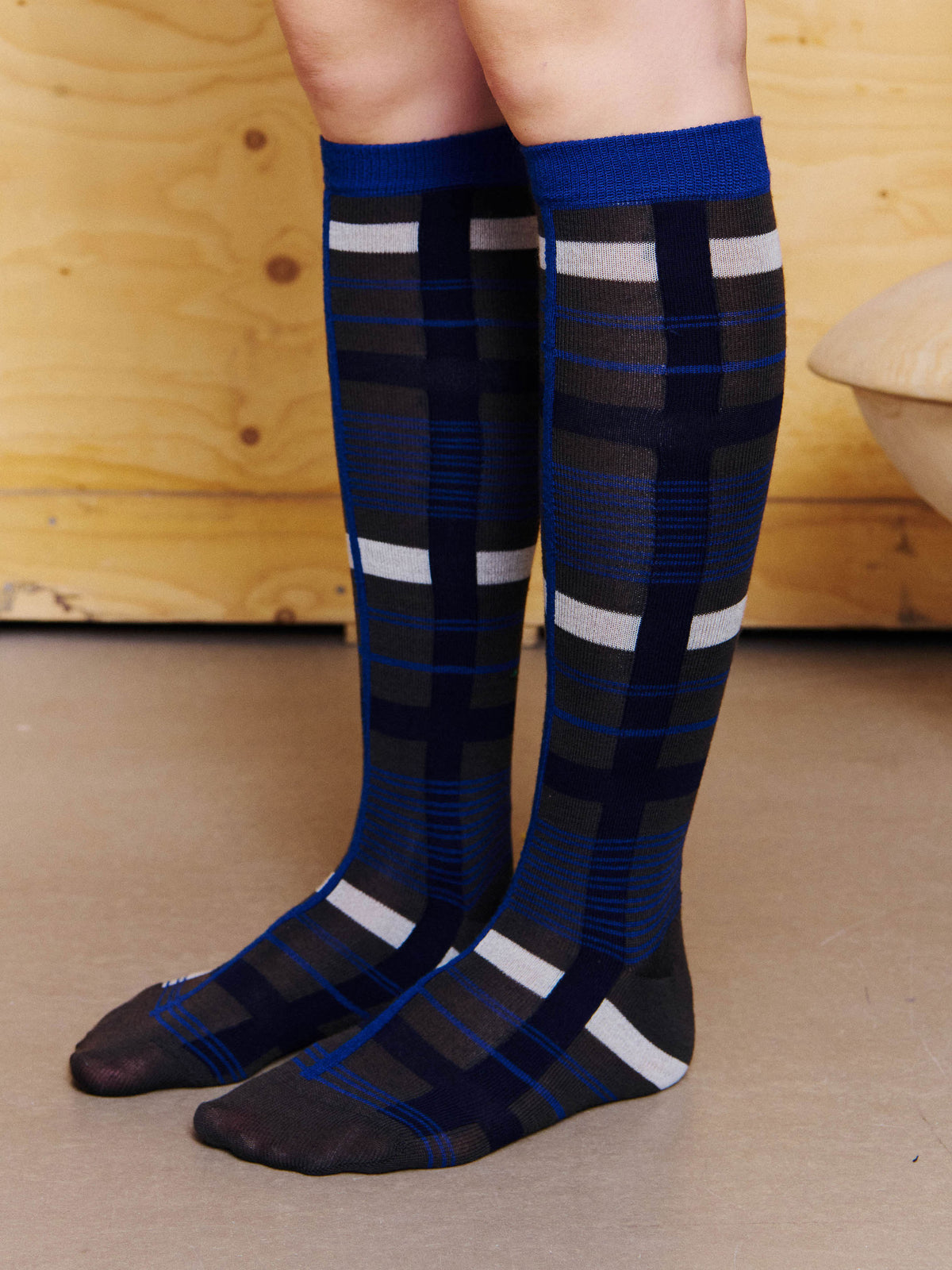Henrik Vibskov Archive Socks in Black Blue Archive worn from the side, showing the knee-high silhouette, check pattern and fitted stretch construction. ID: ARCHIVE-S908