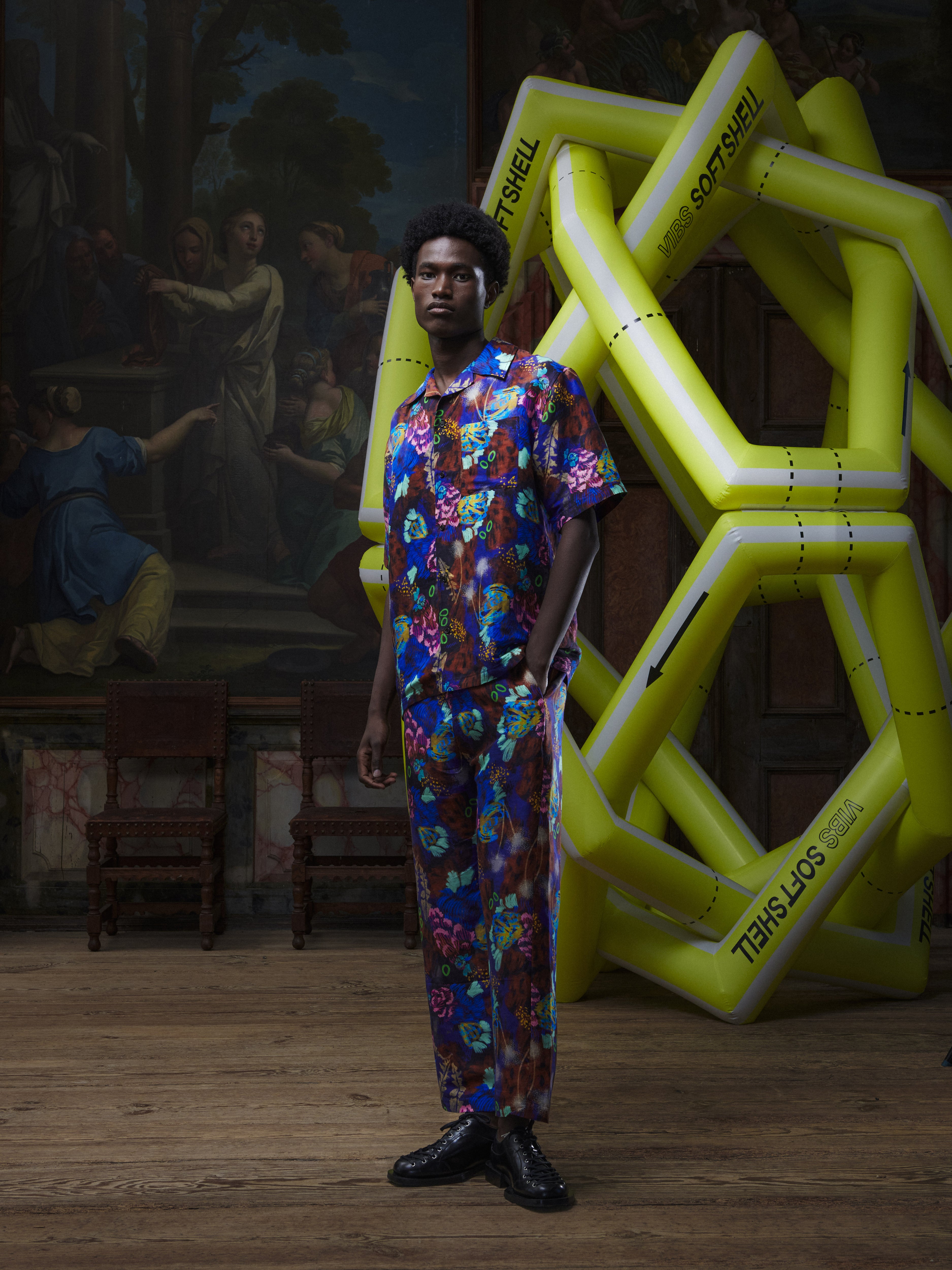 Front view of the male model wearing the Artist Shirt in Space Chickens from Henrik Vibskov Spring/Summer 2026 Studio Collection, showing the colourful print, classic collar, and short sleeves.