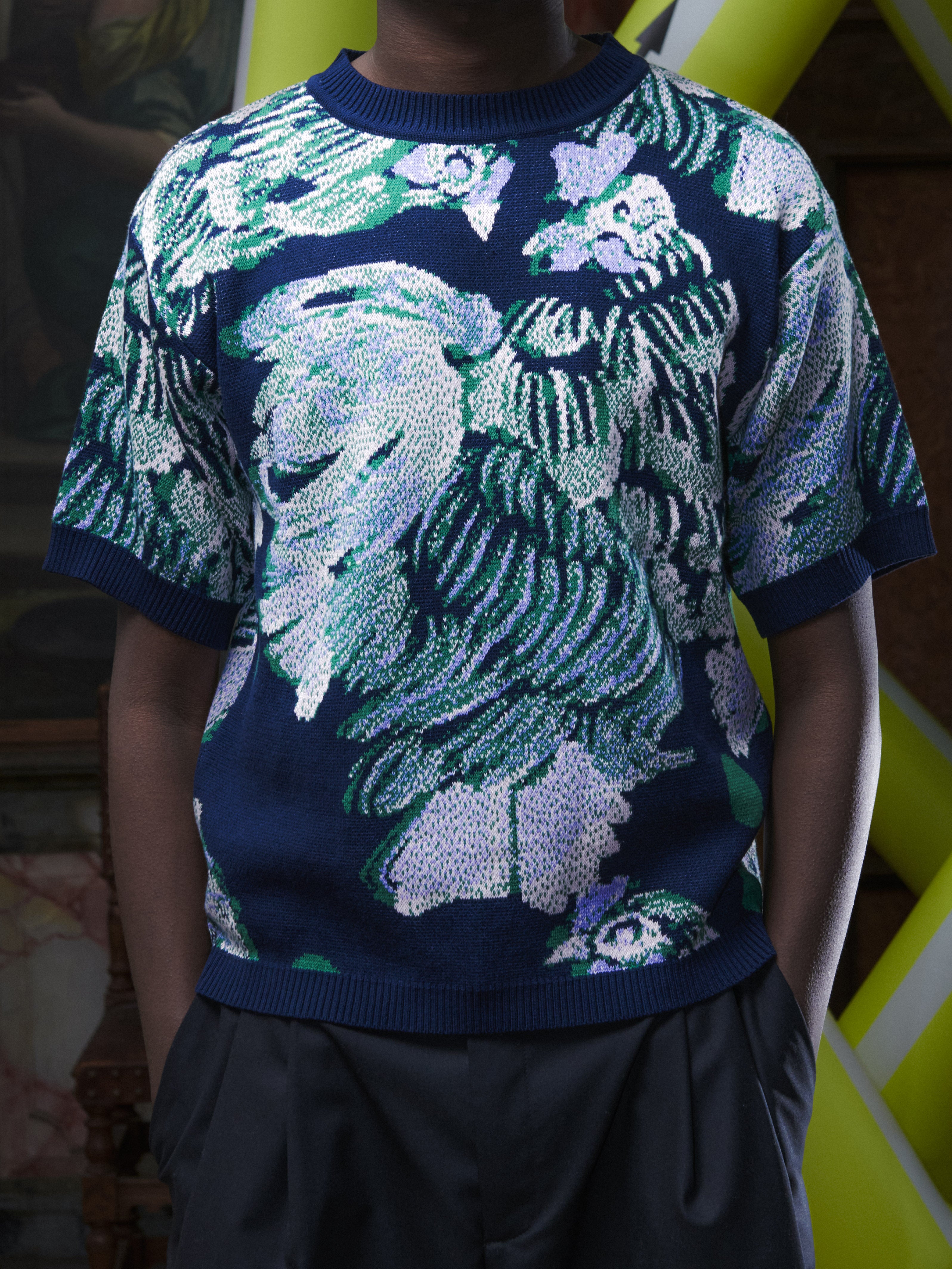 Close-up of the male model wearing the Chicken T Knit in Chicken Navy from Henrik Vibskov Spring/Summer 2026 Studio Collection, focusing on the chicken motif and knitted texture.