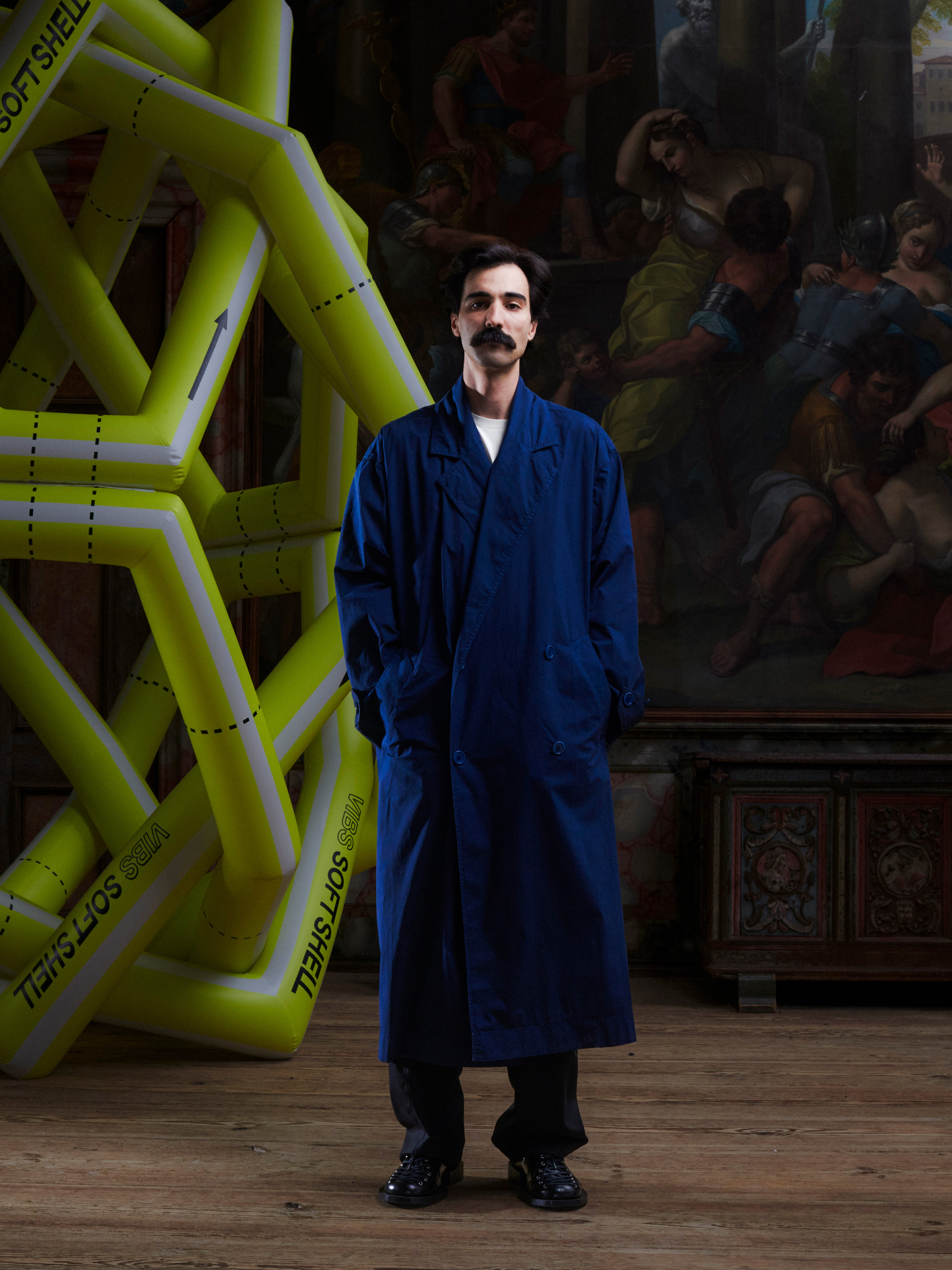 Model wearing the Dimout Long Coat in Navy, front view. Model is 181 cm and wears size M/L, showing the structured blazer collar, double-breasted front, and long tailored fit.