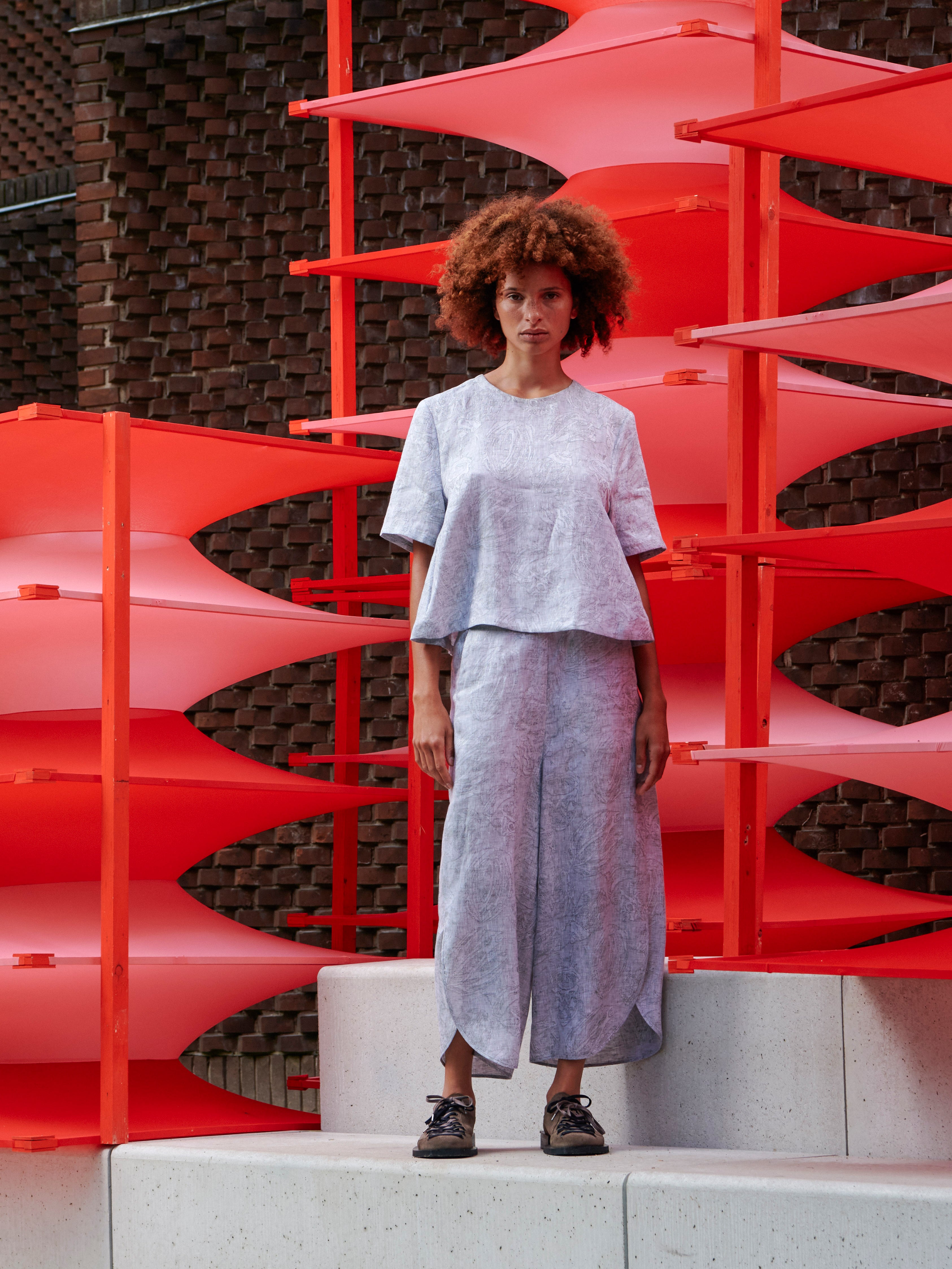 Model wearing the Helmet Top in Bike Helmets grey short sleeve top with subtle texture detail and round neck, front view – Henrik Vibskov Spring/Summer 2026 Key Collection