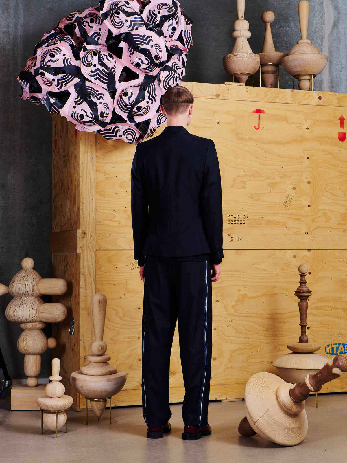 Henrik Vibskov Motif Pants in Black styled on model from the back, showing relaxed tapered fit and contrast side stripe detail. ID: ARCHIVE-M514