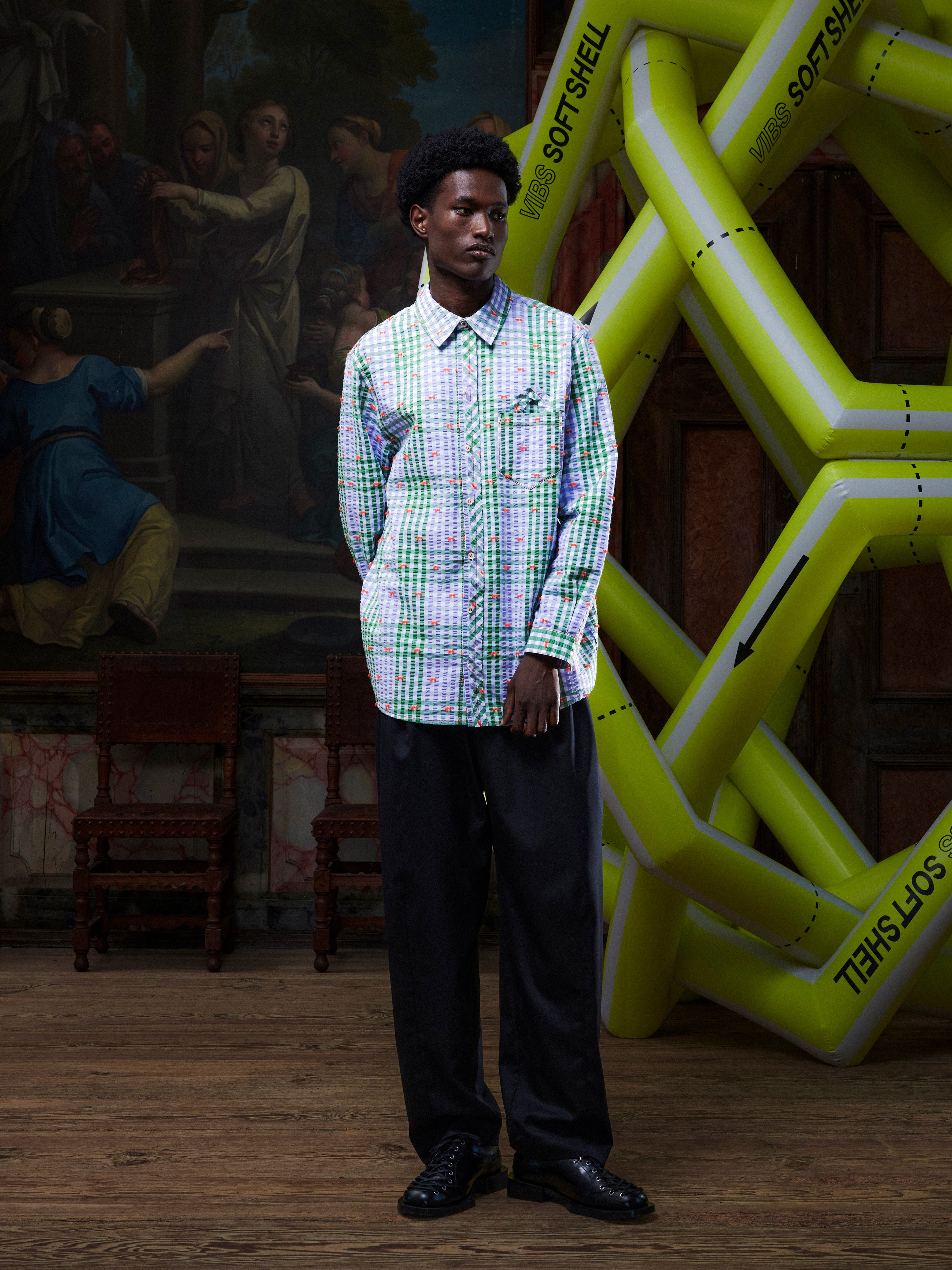 Model wearing the Henrik Vibskov New Blou Shirt in Checks Fillé, front view. The model is 191 cm and wears size M, showing the checked pattern, collar, orange contrast stitching, and relaxed fit.
