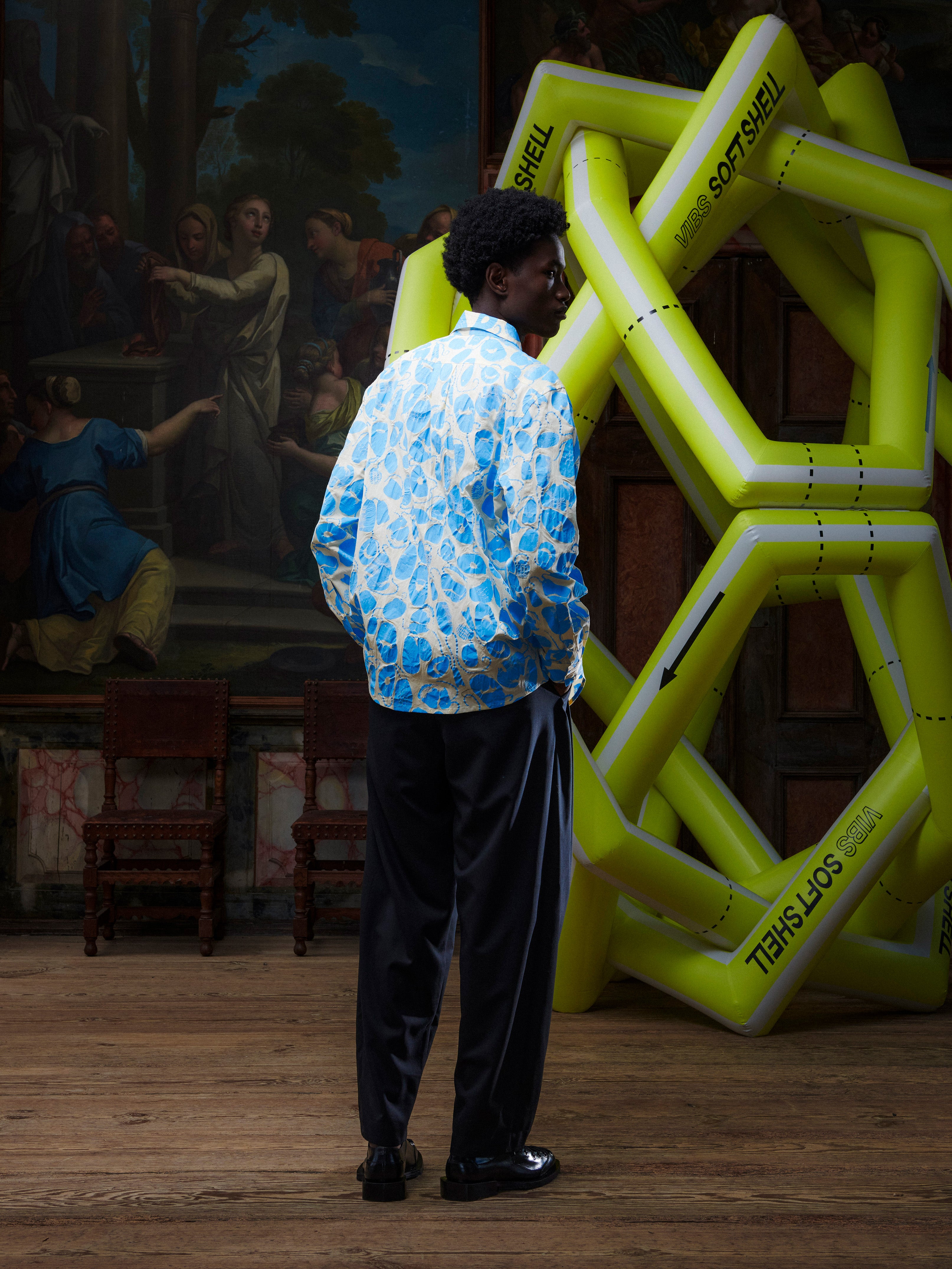 Model wearing the Henrik Vibskov New Blou Shirt in Ecru Amulets, back view, showing the full blue amulets pattern and relaxed silhouette.