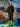 Woman in a black dress standing in front of a colorful abstract wall with blue rocks.