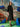 Woman in a black dress standing in front of a colorful abstract wall with blue rocks.