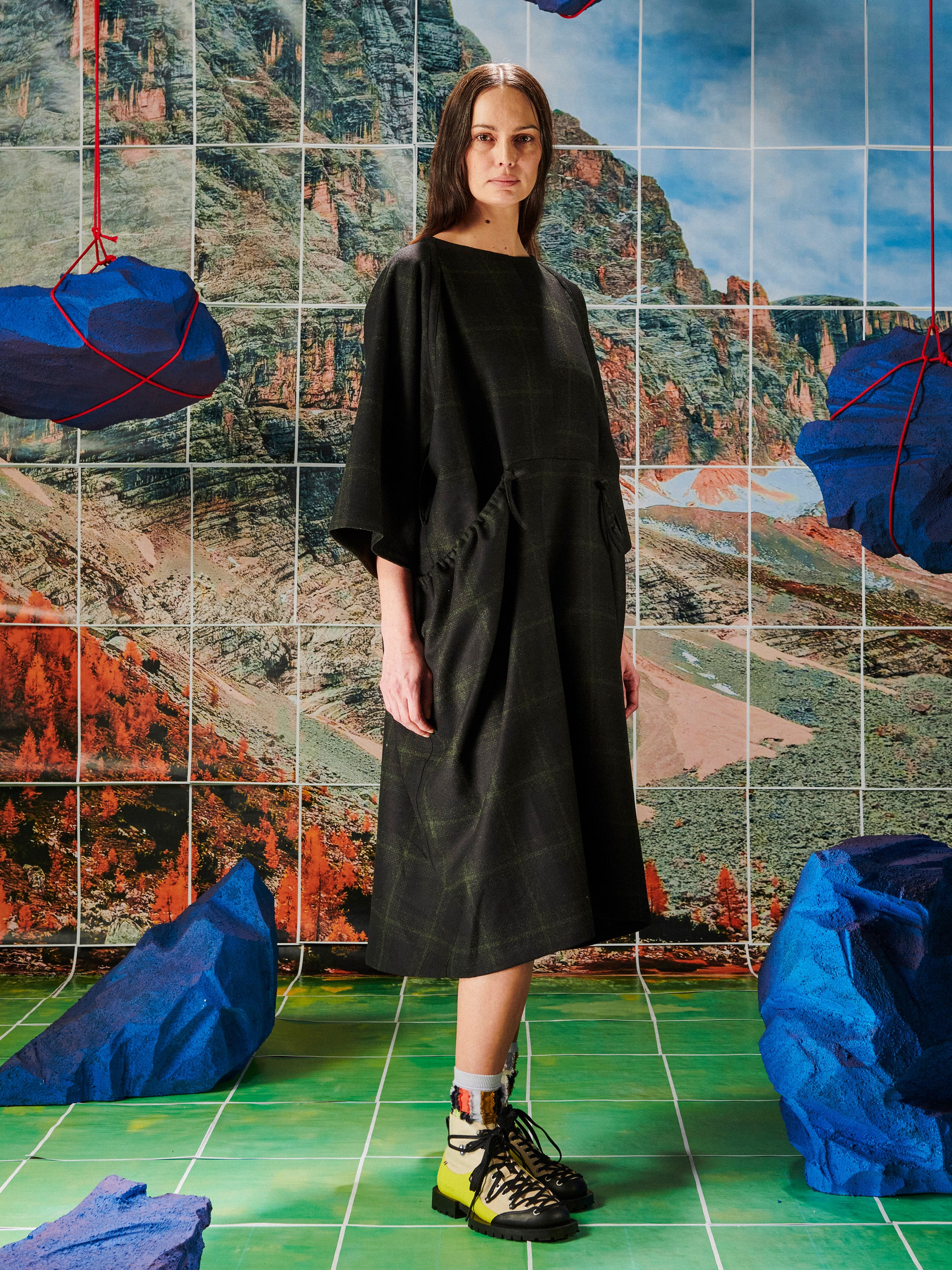 Woman in a black dress standing in front of a colorful abstract wall with blue rocks.