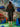 Woman in a black dress standing in front of a colorful abstract wall with blue rocks.