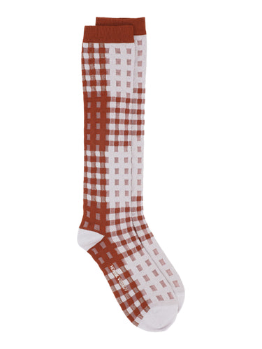 Checkered knee-high socks with rust and white pattern on a white background