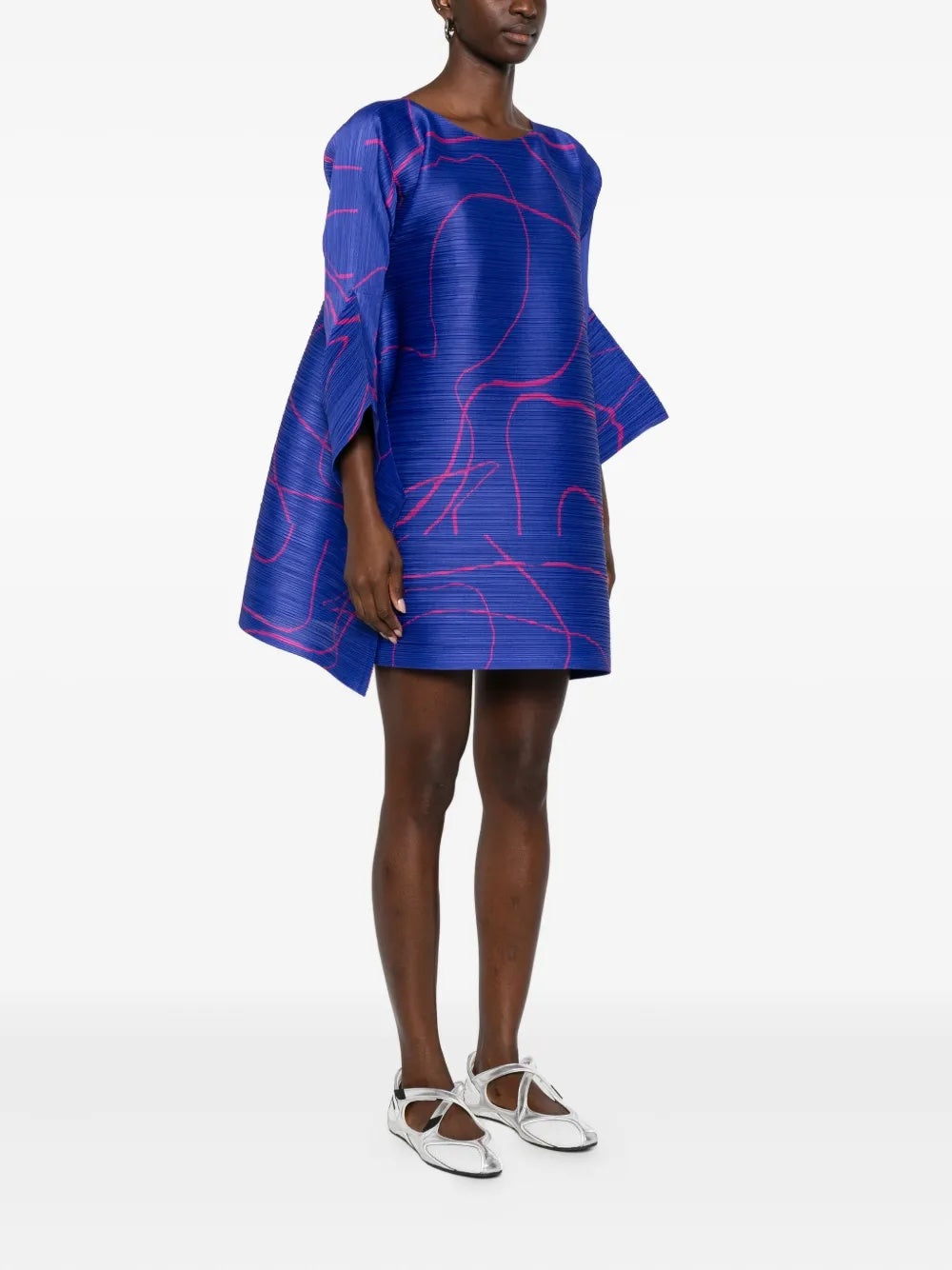 Woman wearing a blue dress with pink abstract patterns on a white background
