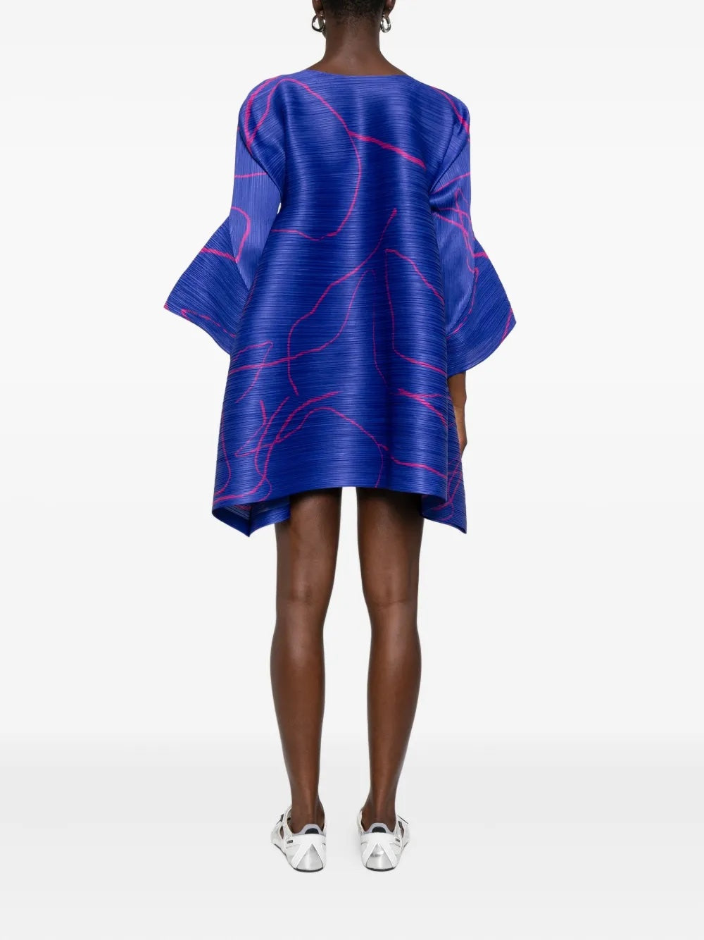Person wearing a blue dress with pink patterns on a white background
