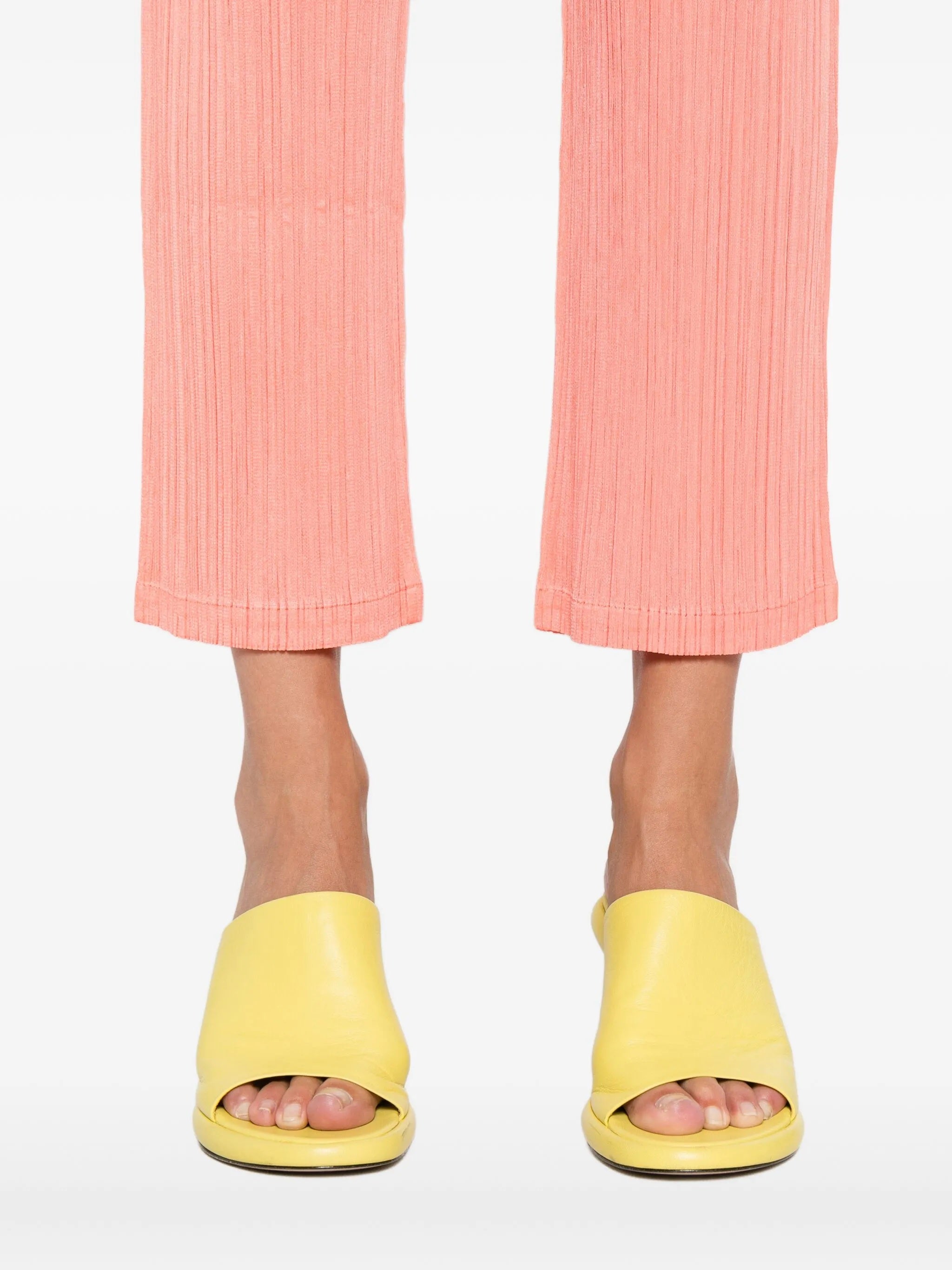 Yellow sandals worn with pink pants on a white background