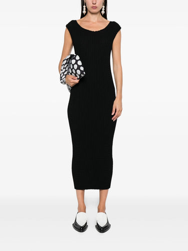 Woman wearing a black dress holding a polka dot clutch on a white background