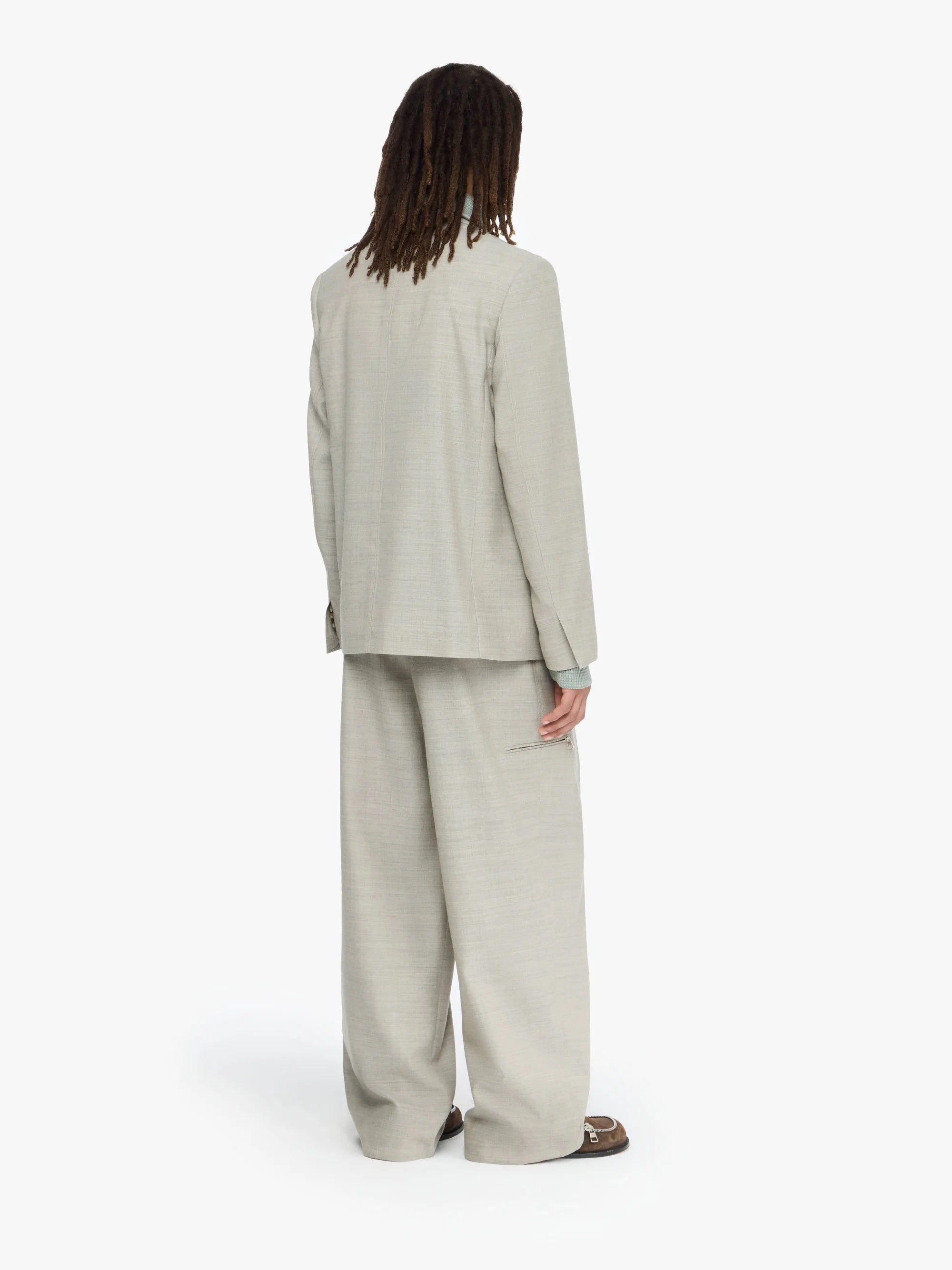 Person wearing a beige suit standing against a white background