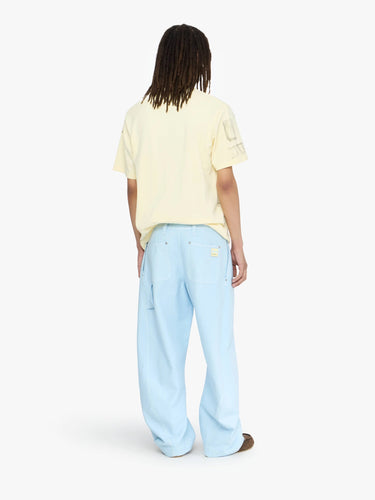 Person wearing a light yellow shirt and light blue pants on a white background