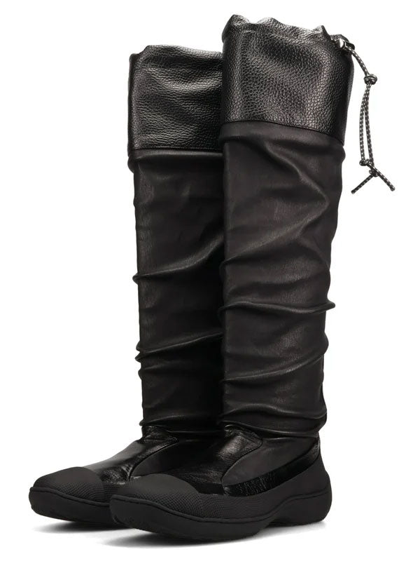 Kiko Kostadinov Avocet Leather Boots in Ink Black shown as a pair from the front, featuring tall ruched leather shafts, adjustable drawcord detailing, rounded toes and sculpted black rubber soles.