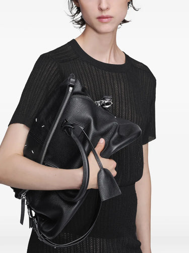 Maison Margiela 5AC Soft Medium in black, model view, carried by hand showing soft grained leather and tassel zip pulls