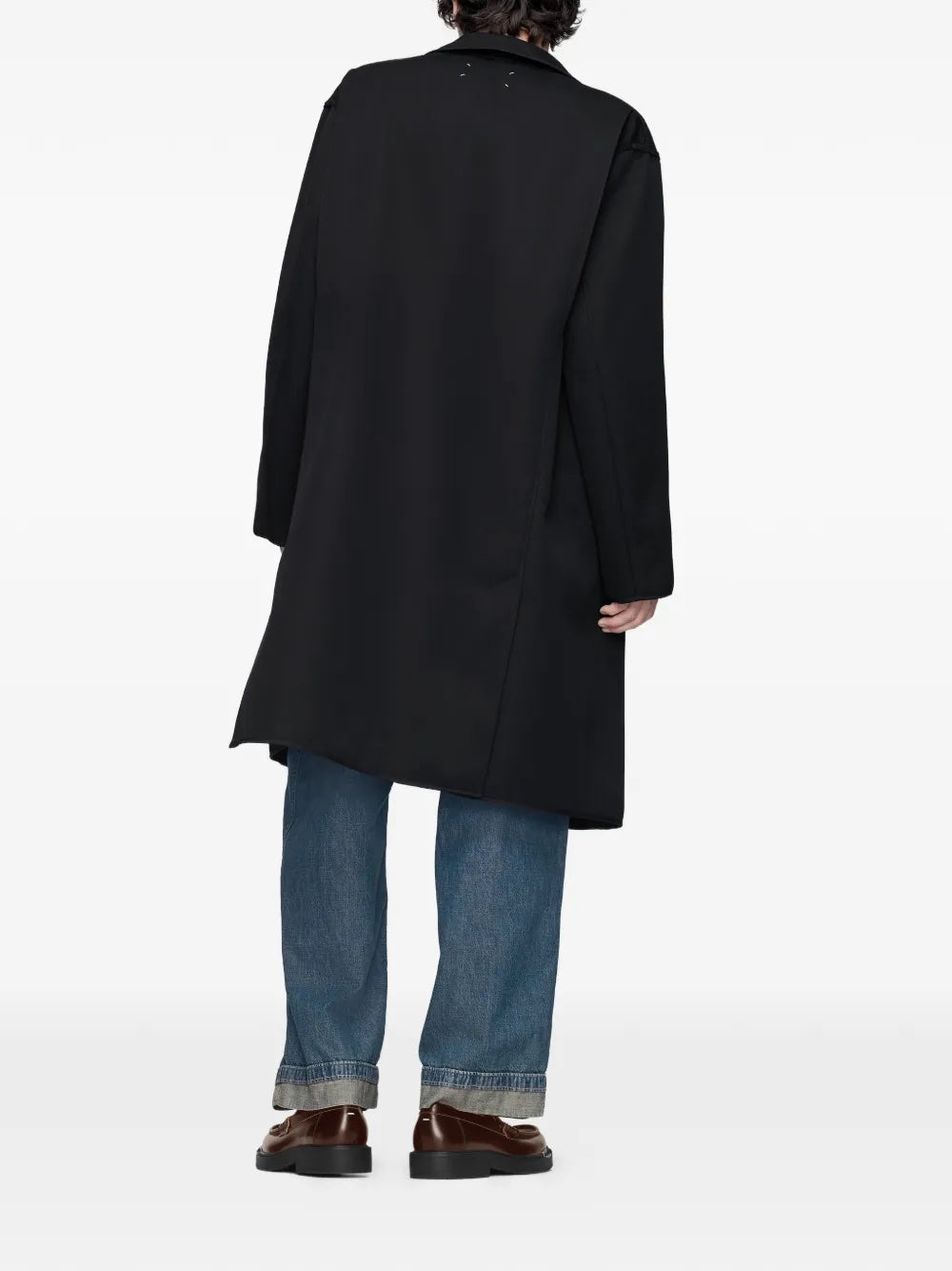 Back view of model wearing Maison Margiela black and grey check coat showing inside-out design and long sleeves