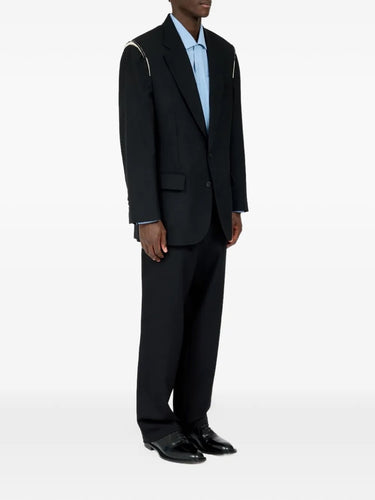 Male model wearing Maison Margiela Black Blazer, side view, showing structured shoulder detail and sleek silhouette.