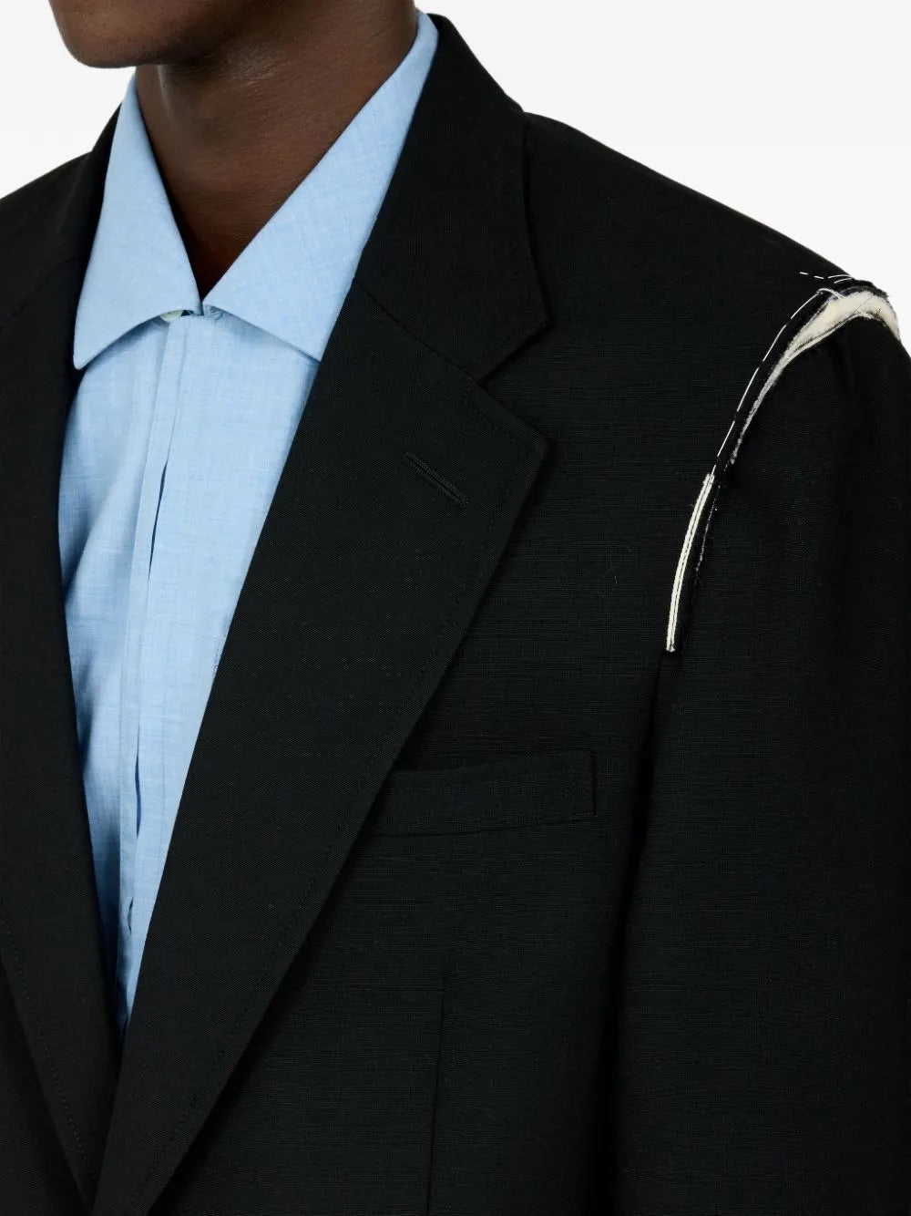 Closeup of male model wearing Maison Margiela Black Blazer from the side, showing shoulder detail, button fastening, and fine virgin wool texture.