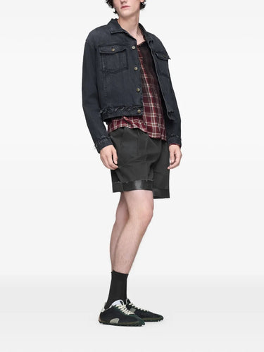 Front view of a model wearing the washed black Maison Margiela sports jacket, showing the cropped fit, buttoned front, and distressed denim texture.