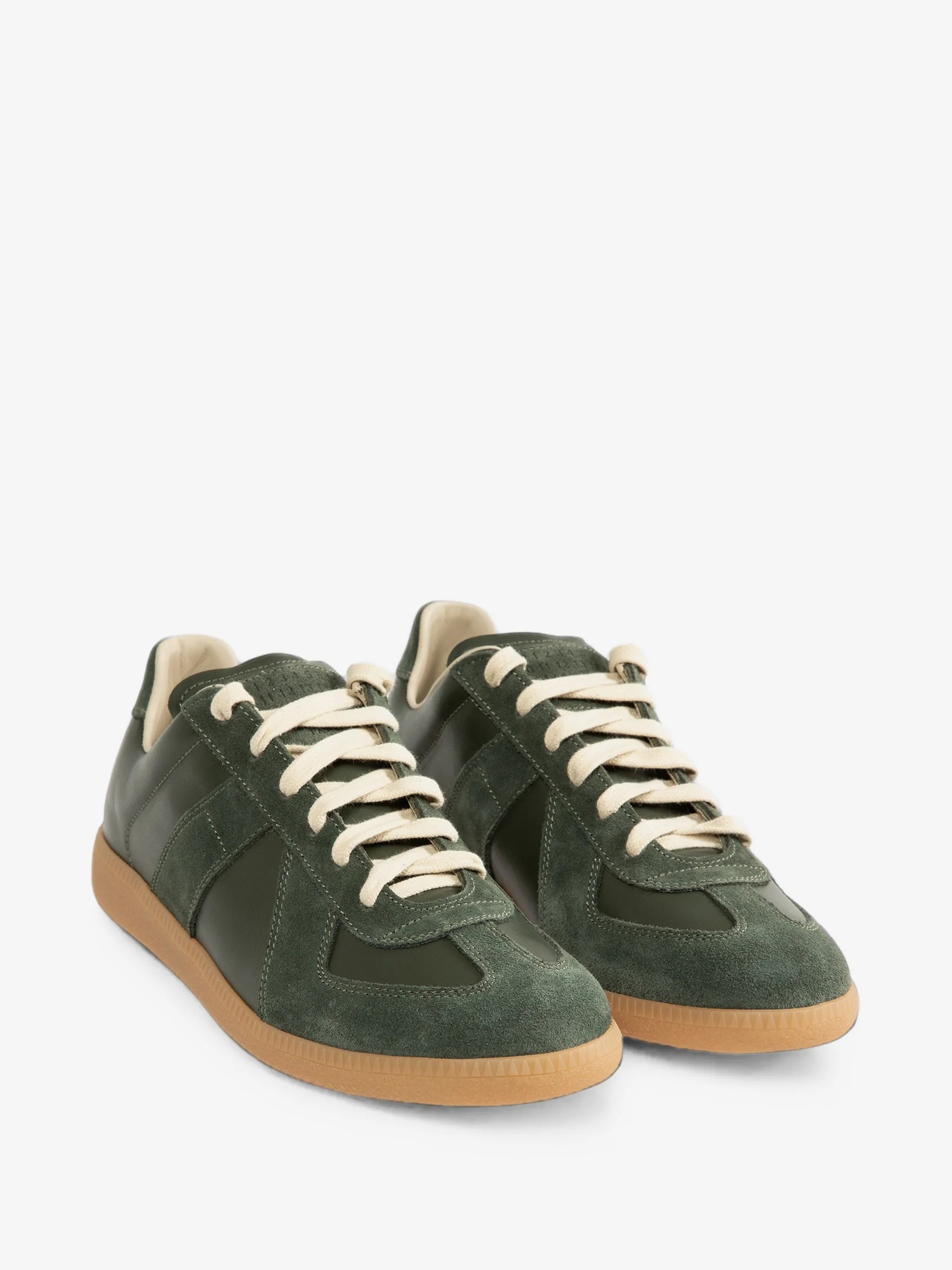 A pair of forest green Replica sneakers from Maison Margiela on a grey background