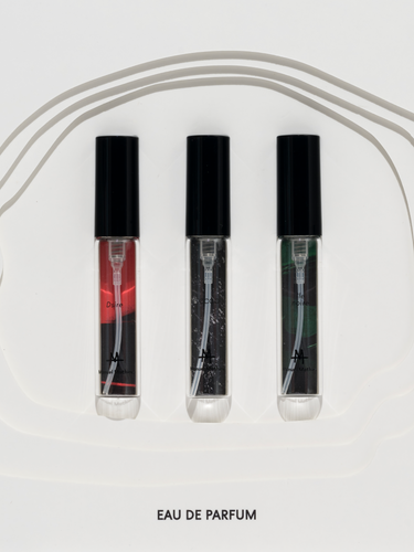 Three small perfume bottles with black caps on a white background