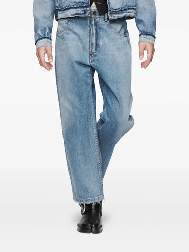 Closer front view of a male model wearing the Maison Margiela Pants 5 Pockets in Washed Blue, showing the raw-cut hem, button and fly fastening, belt loops, and detailed five-pocket styling.