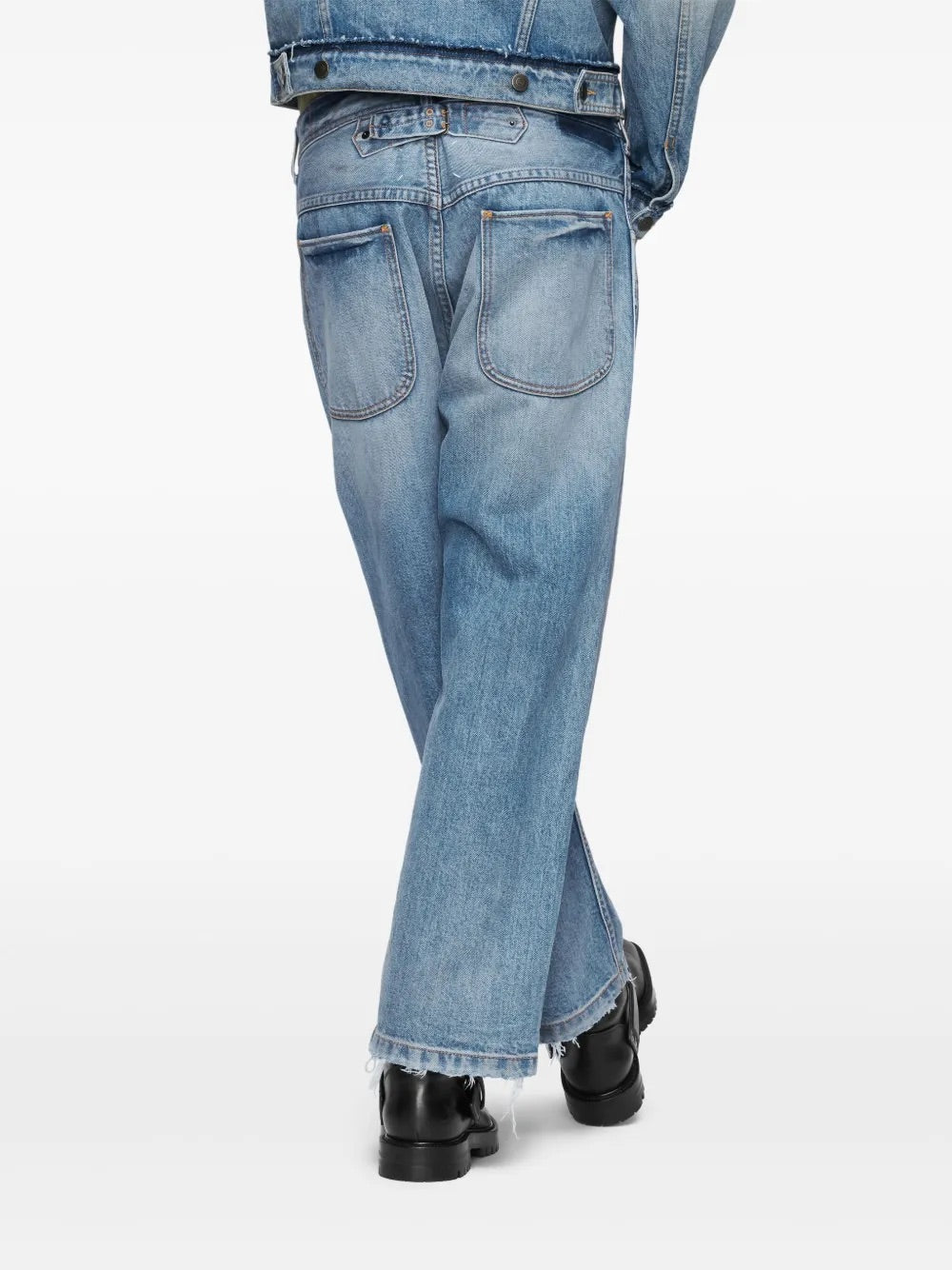 Back view of a male model wearing the Maison Margiela Pants 5 Pockets in Washed Blue, showing the rear pockets, waistband, and raw-cut hem of the straight-leg jeans.