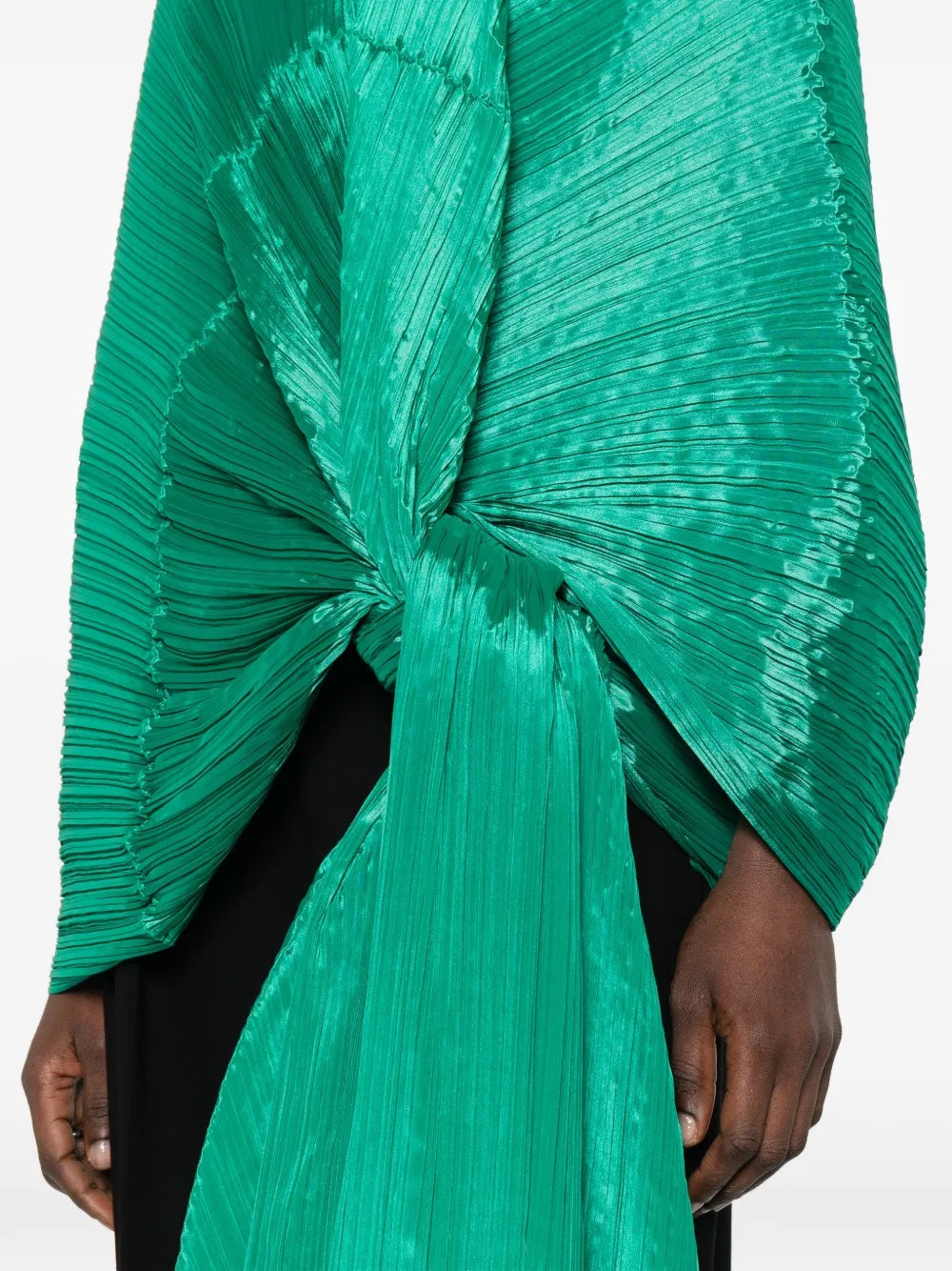 Close-up of a model wearing the green pleated top called Madam T by Pleats Please Issey Miyake on a white background