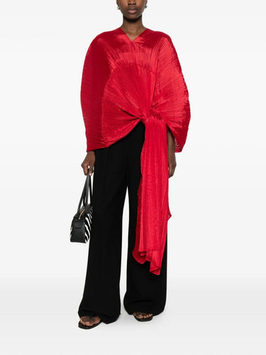 Model wearing the red pleated top called Madam T by Pleats Please Issey Miyake on a white background