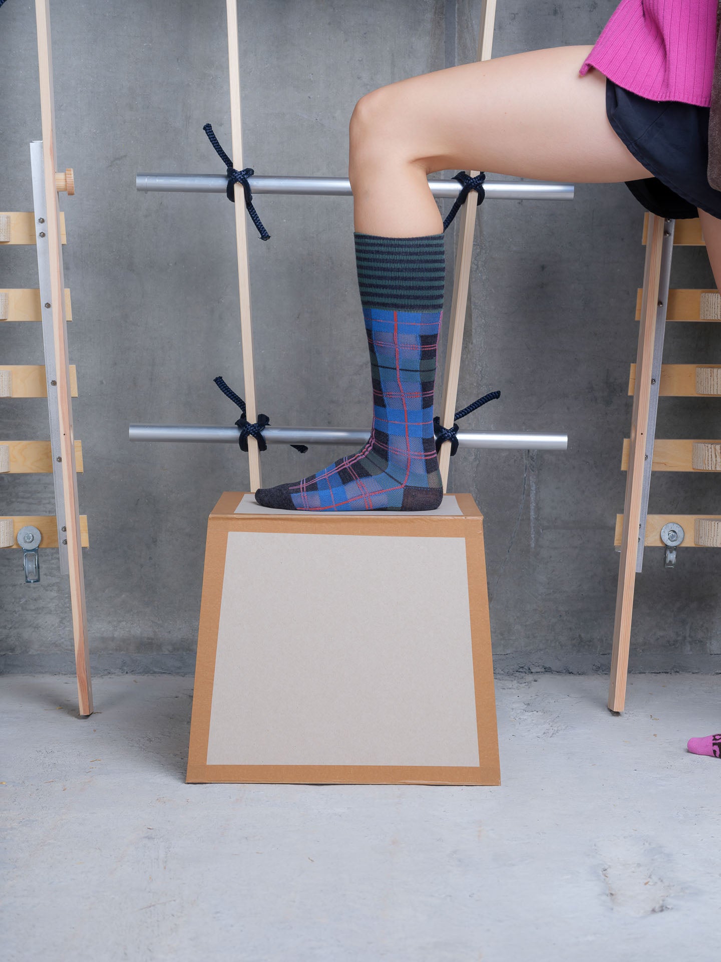Model wearing Ribbit Knee Sock in Green Blue Dashed Checks by Henrik Vibskov