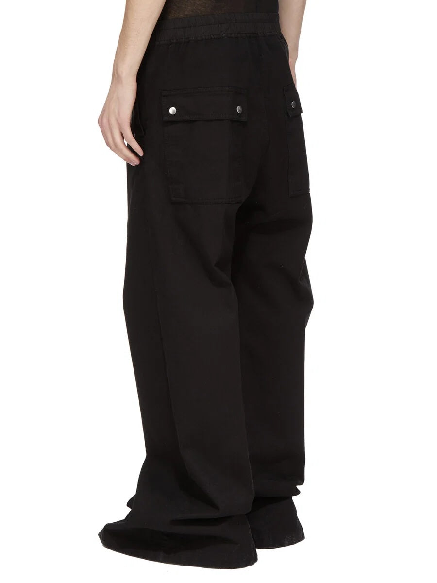 Rick Owens DRKSHDW Geth Belas in black shown on model from the back side angle with back flap pockets and wide full-length legs.