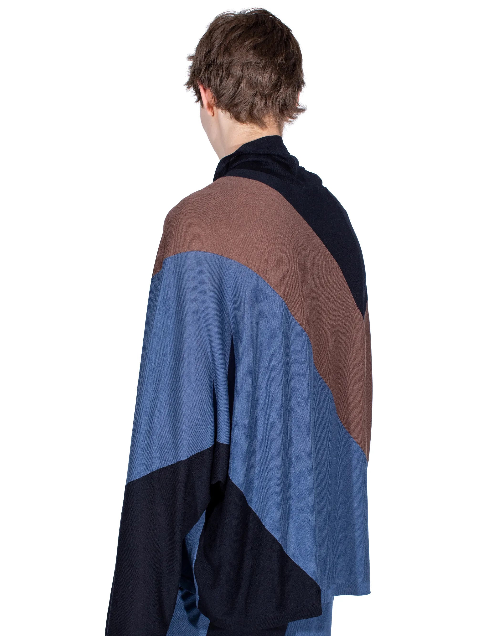 Back and side view of model wearing Kiko Kostadinov SIGO Knit Top in navy, brown and blue, showing relaxed silhouette, dolman sleeves and chevron stripe transition across the back and sleeves