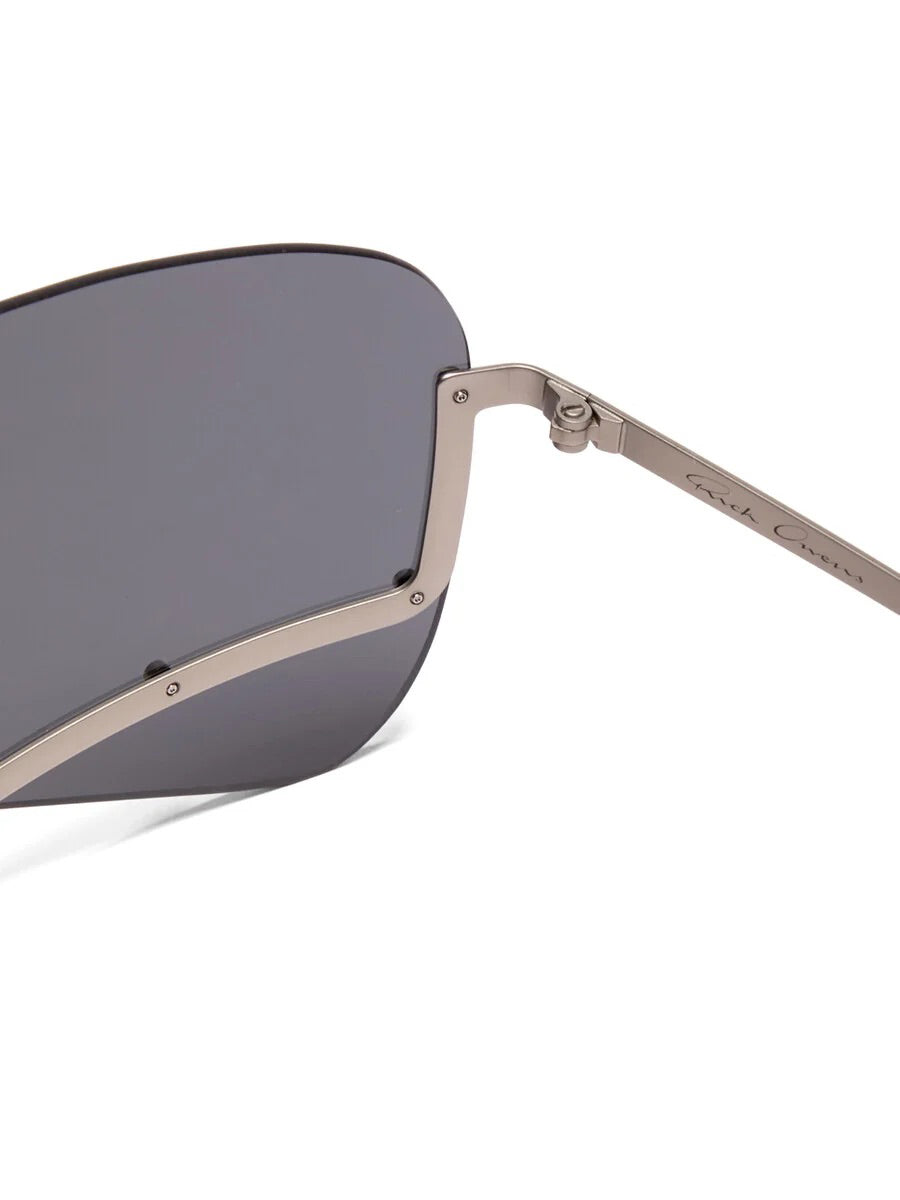 Close-up of Rick Owens Tower Sunglasses showing the riveted stainless steel frame, black lens and logo detail on the temple.