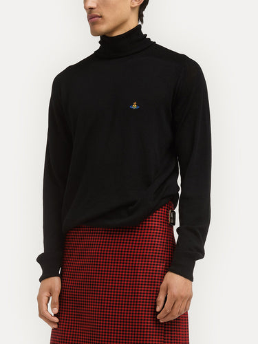 Person wearing a black turtleneck sweater with a small logo and a red checkered skirt on a white background