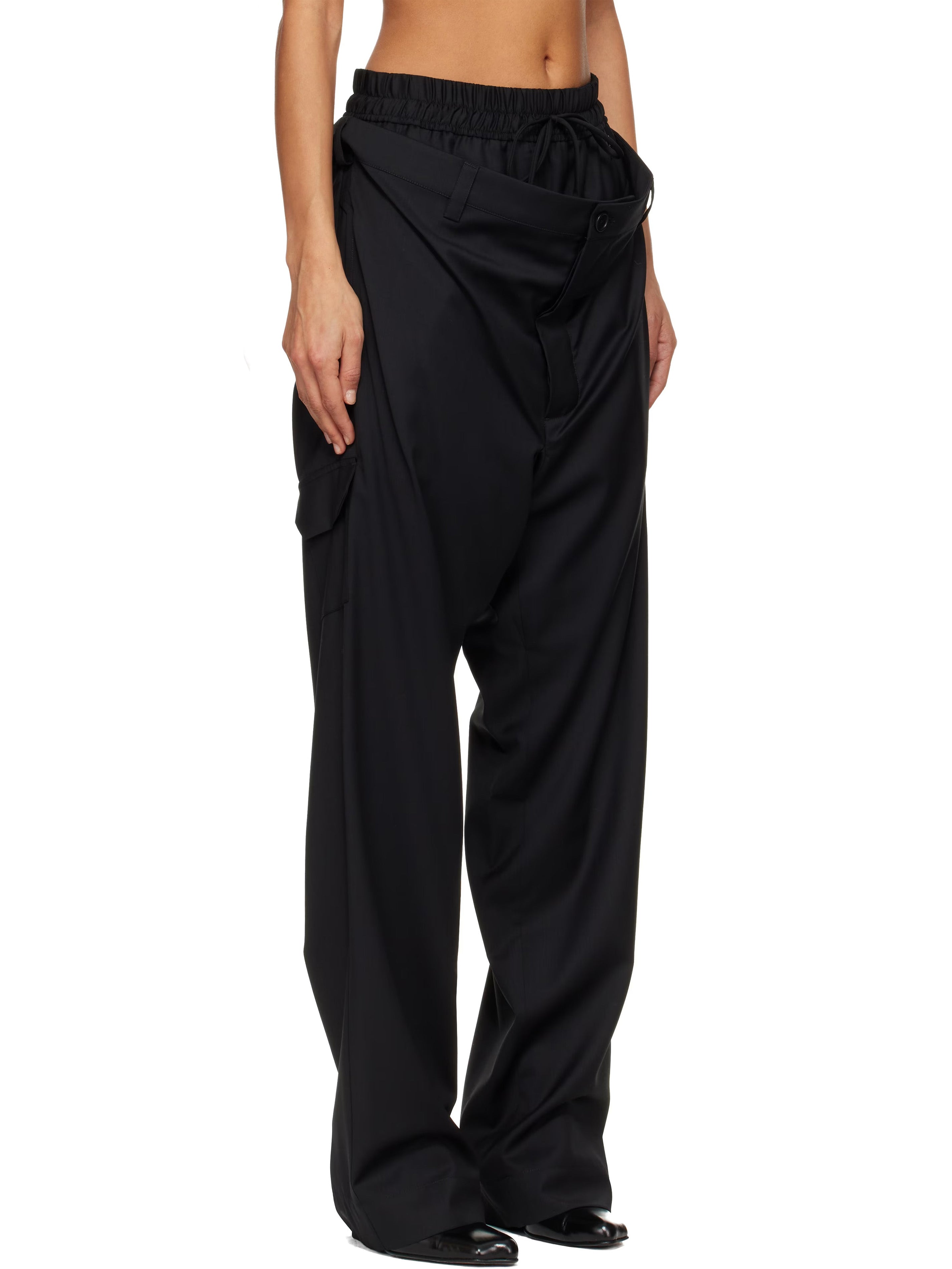 Cropped, side view of model wearing the black, layered-design trousers from Vivienne Westwood on a white background