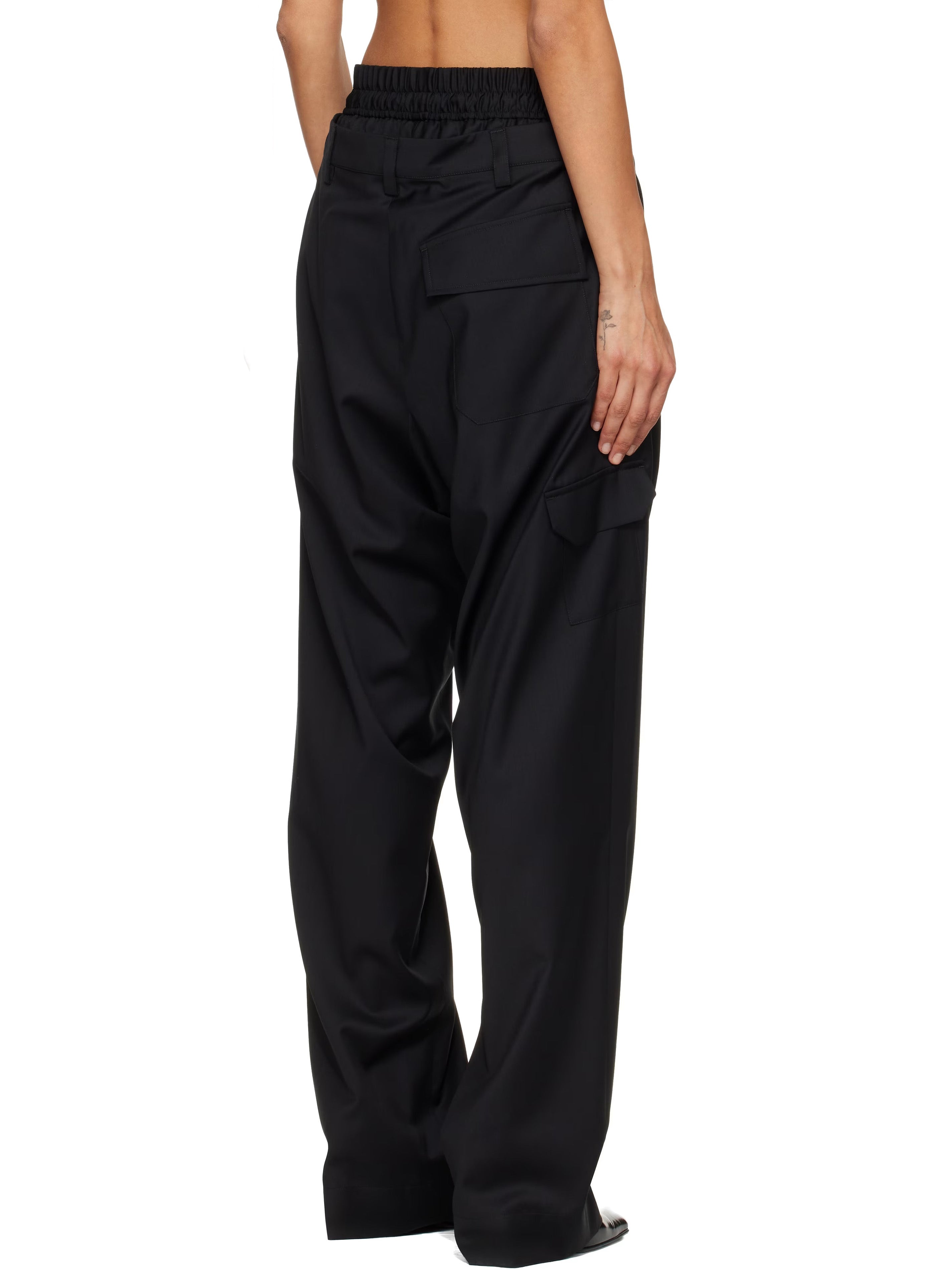 Cropped, back view of model wearing the black, layered-design trousers from Vivienne Westwood on a white background