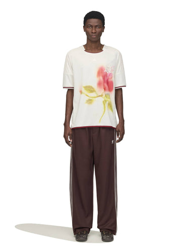 Model wearing the Wales Bonner x Adidas Track Pants in Shadow Brown shadow brown wide-leg track pants with white three-stripe detail and elasticated waistband, front view – Wales Bonner x Adidas SS26