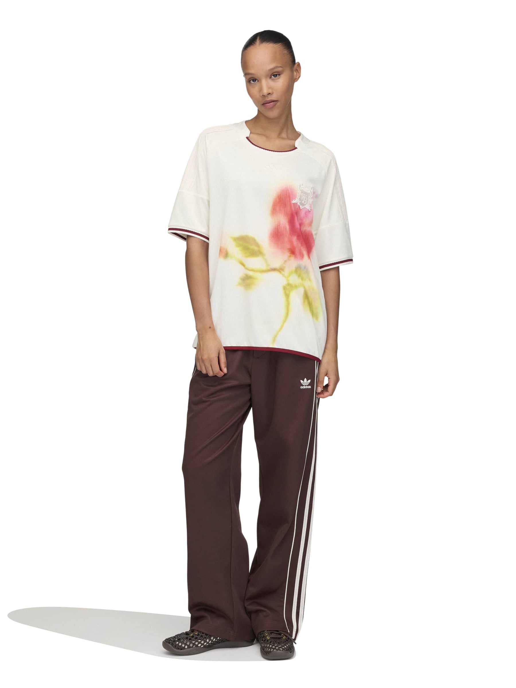 Model wearing the Wales Bonner x Adidas Track Pants in Shadow Brown shadow brown wide-leg track pants with elasticated waistband and white three-stripe detail, full length front view – Wales Bonner x Adidas SS26
