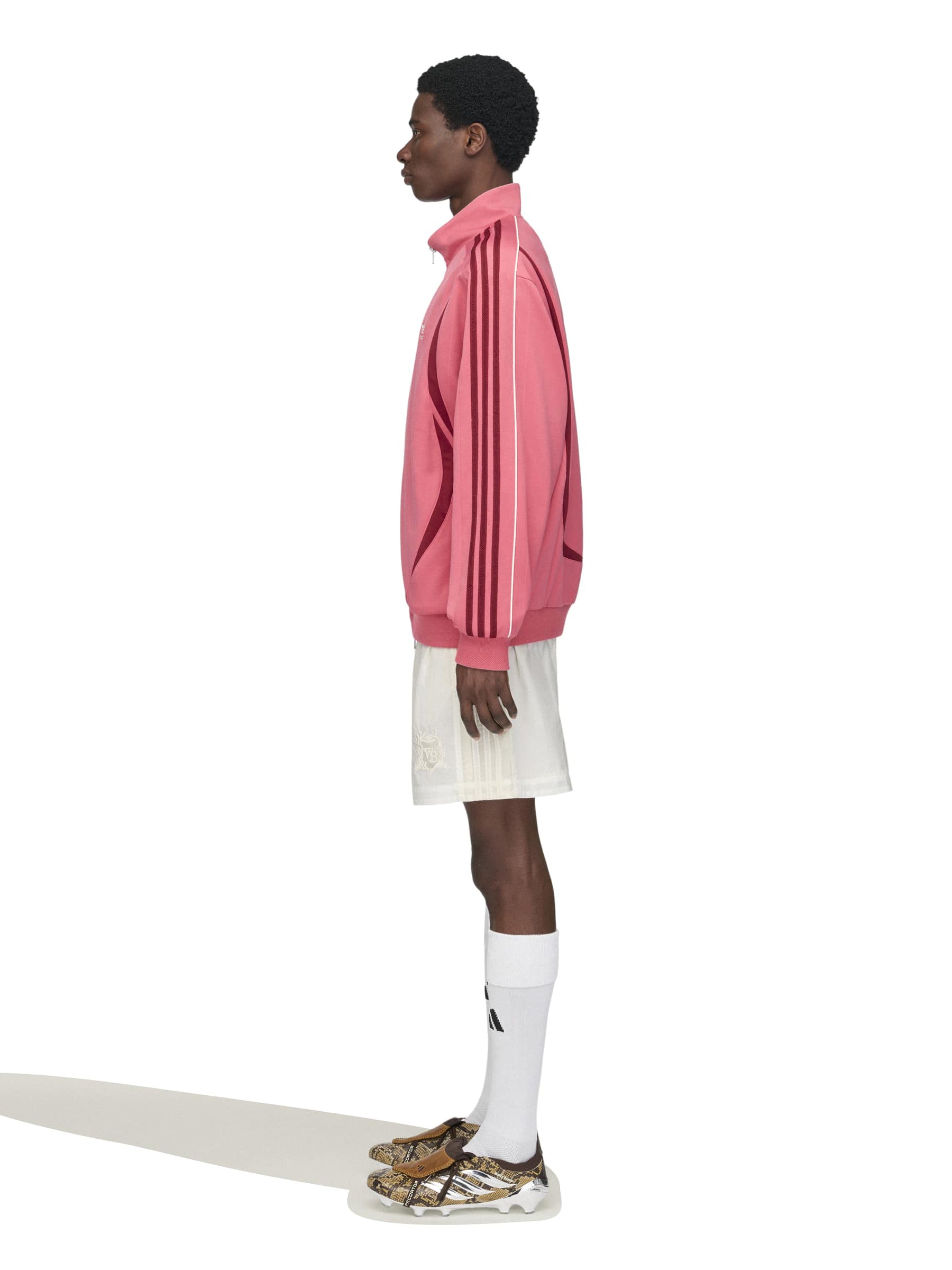 Model wearing the Wales Bonner x Adidas Track Top in Craft Pink pink track jacket with ribbed cuffs and zip side pockets, side view – Wales Bonner x Adidas SS26