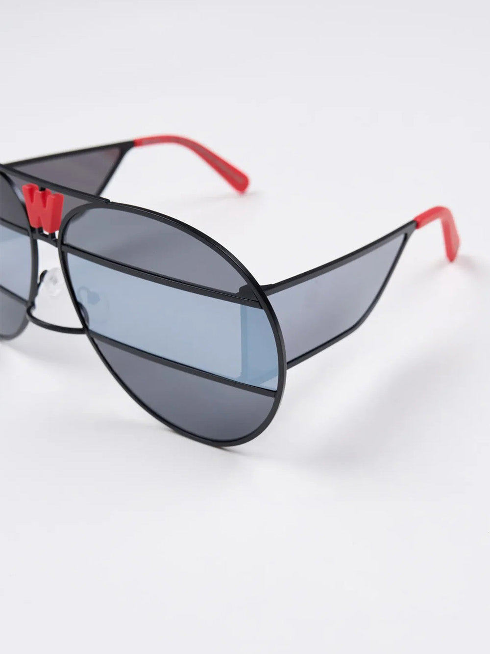 Walter Van Beirendonck x Komono Brutal Pilot sunglasses, three-quarter view, striped multi-panel mirror lenses and red W monogram bridge detail
