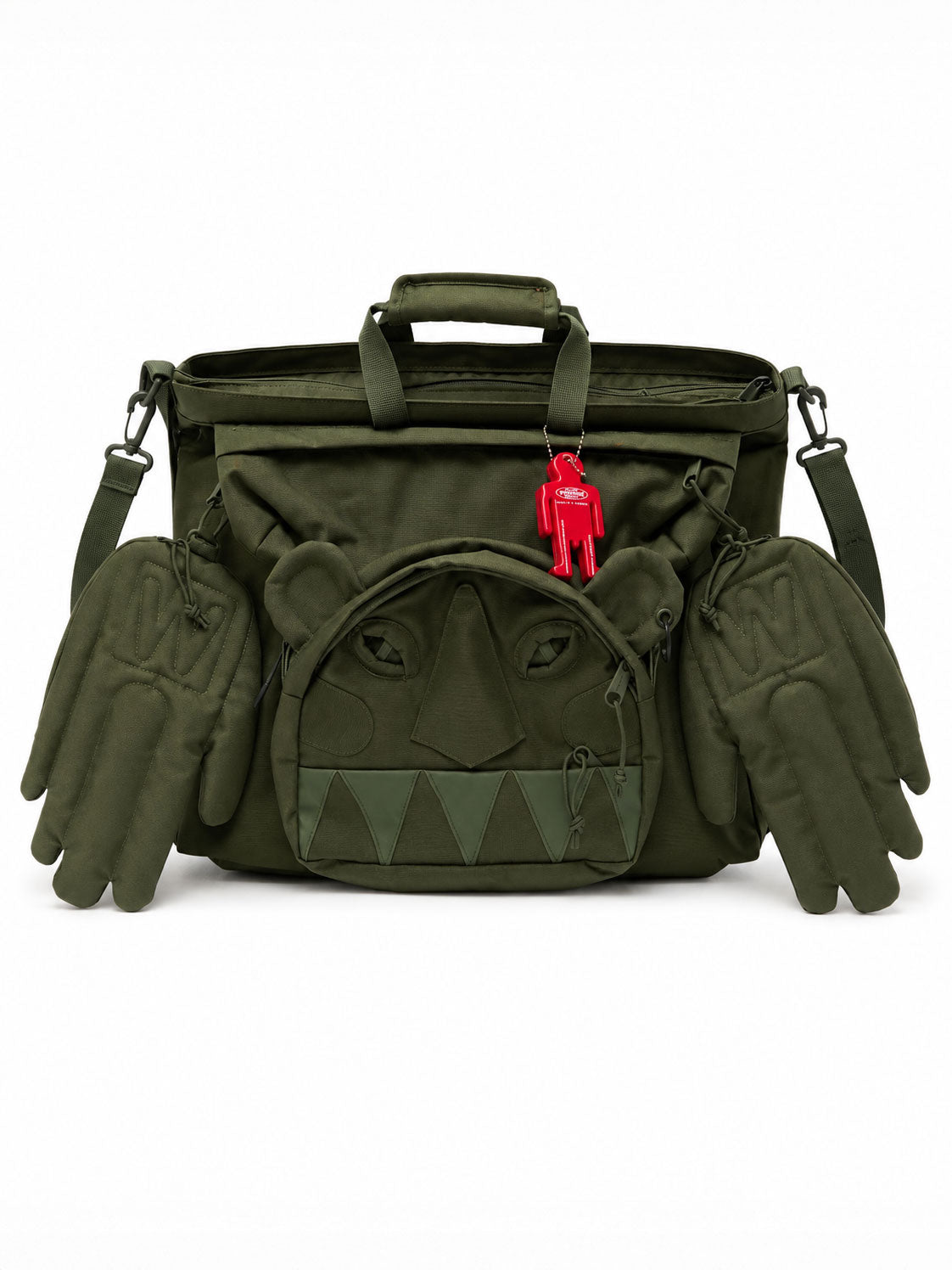 Walter Van Beirendonck Monster Carry Bag in military green with sculptural monster face, padded hand pockets, shoulder strap and red character charm.