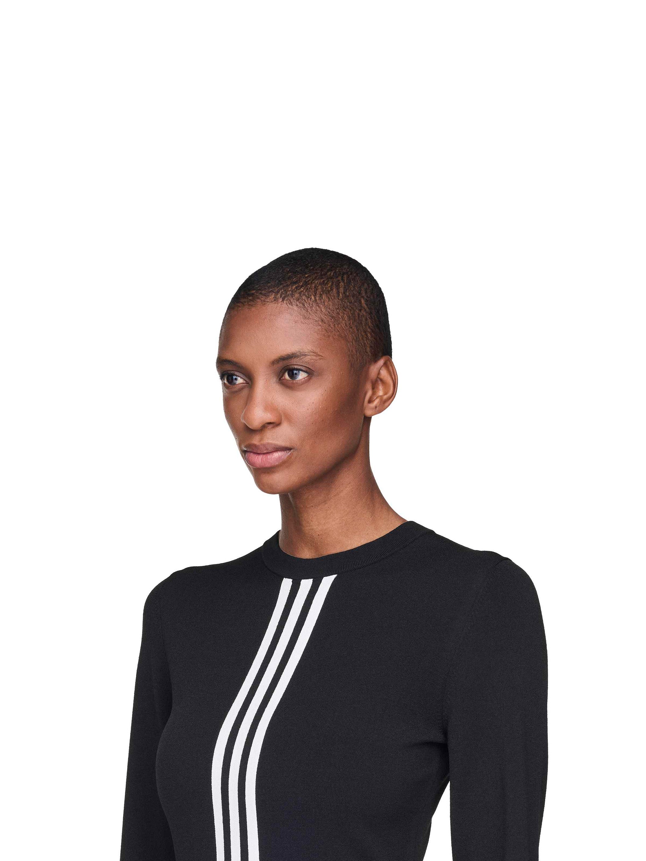 Person wearing a black long-sleeve top with white stripes on a white background