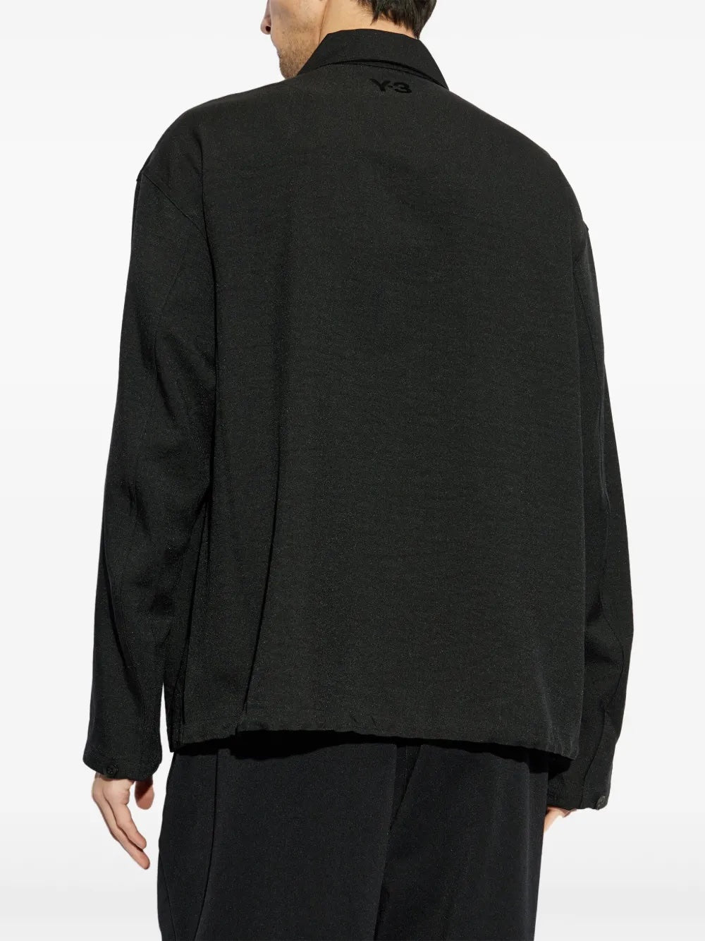 Person wearing a black jacket and pants on a white background